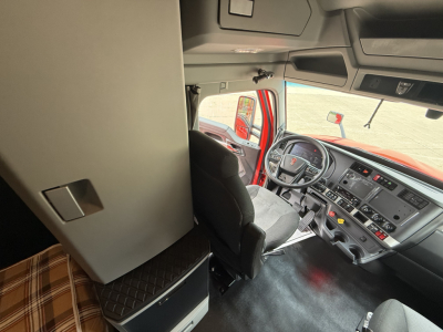 Kenworth T680 truck cab interior showing steering wheel and dashboard with sleeper area and storage cabinet