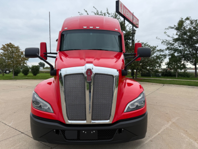 Kenworth T680 truck front view showing bold chrome grille, red cab, and black bumper; headlights and large side mirrors visible.