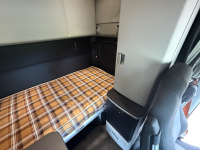Kenworth T680 sleeper cab interior with plaid bed cover and storage cabinet