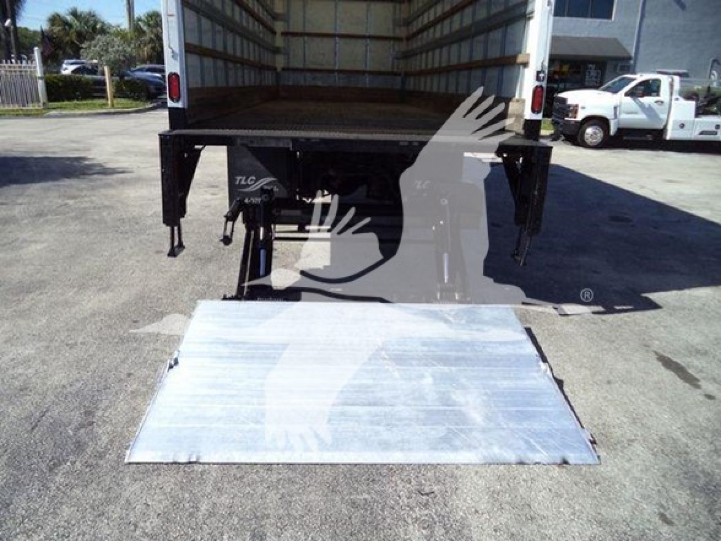Truck with a rear aluminum ramp lowered, International Durastar 4300 box truck, cargo area visible, hydraulic lift legs.