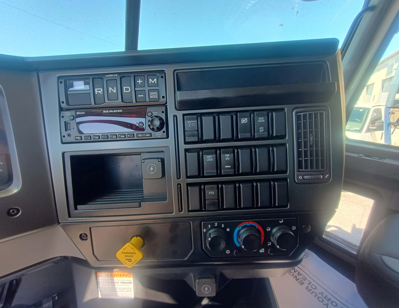 Dashboard of a 2027 Mack GR84F dump truck showing instrument cluster, switches, and climate controls with yellow key switch visible.