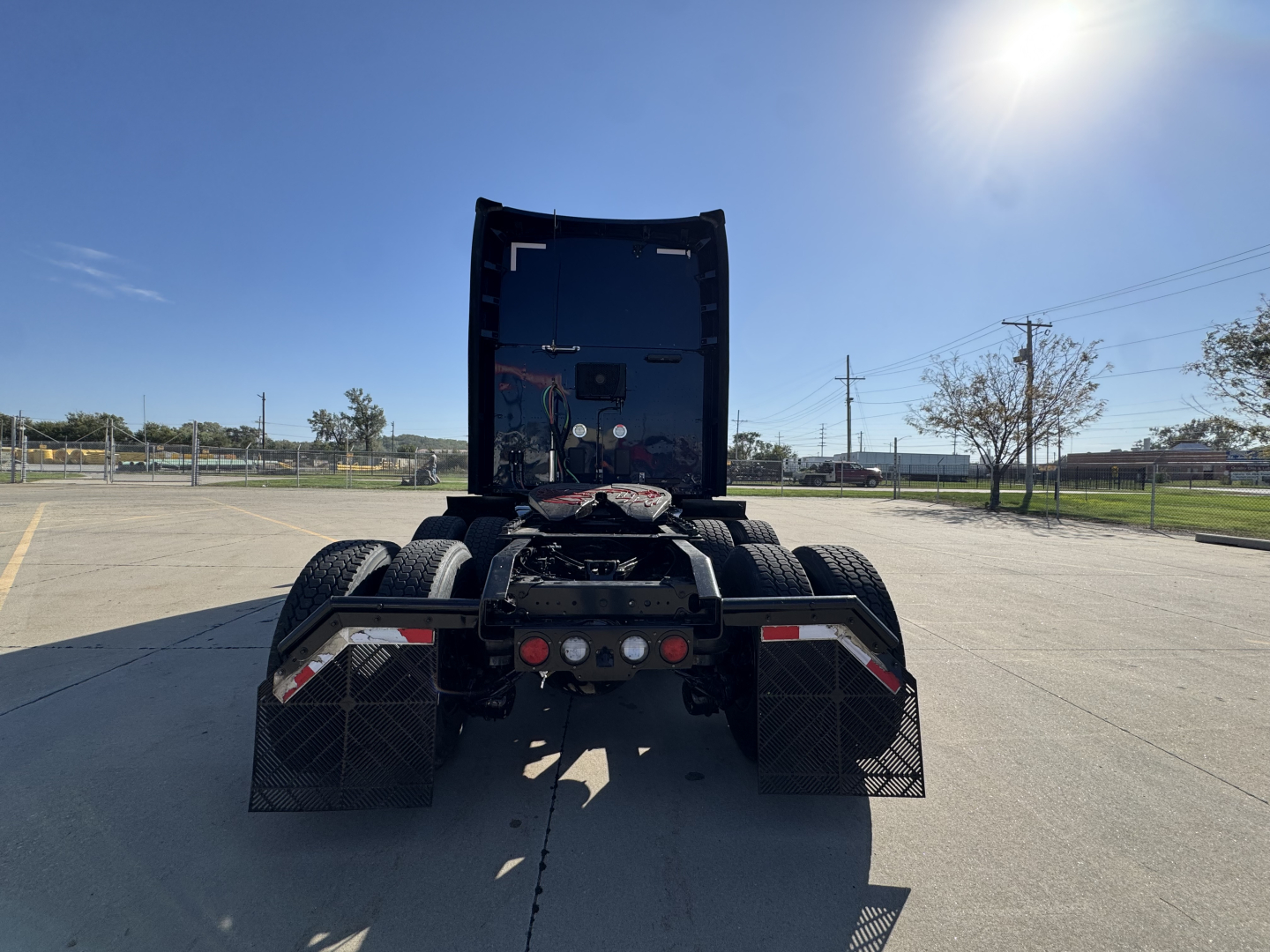 Kenworth T680 rear view showing fifth wheel, dual rear axles, and mudflaps in a paved lot.