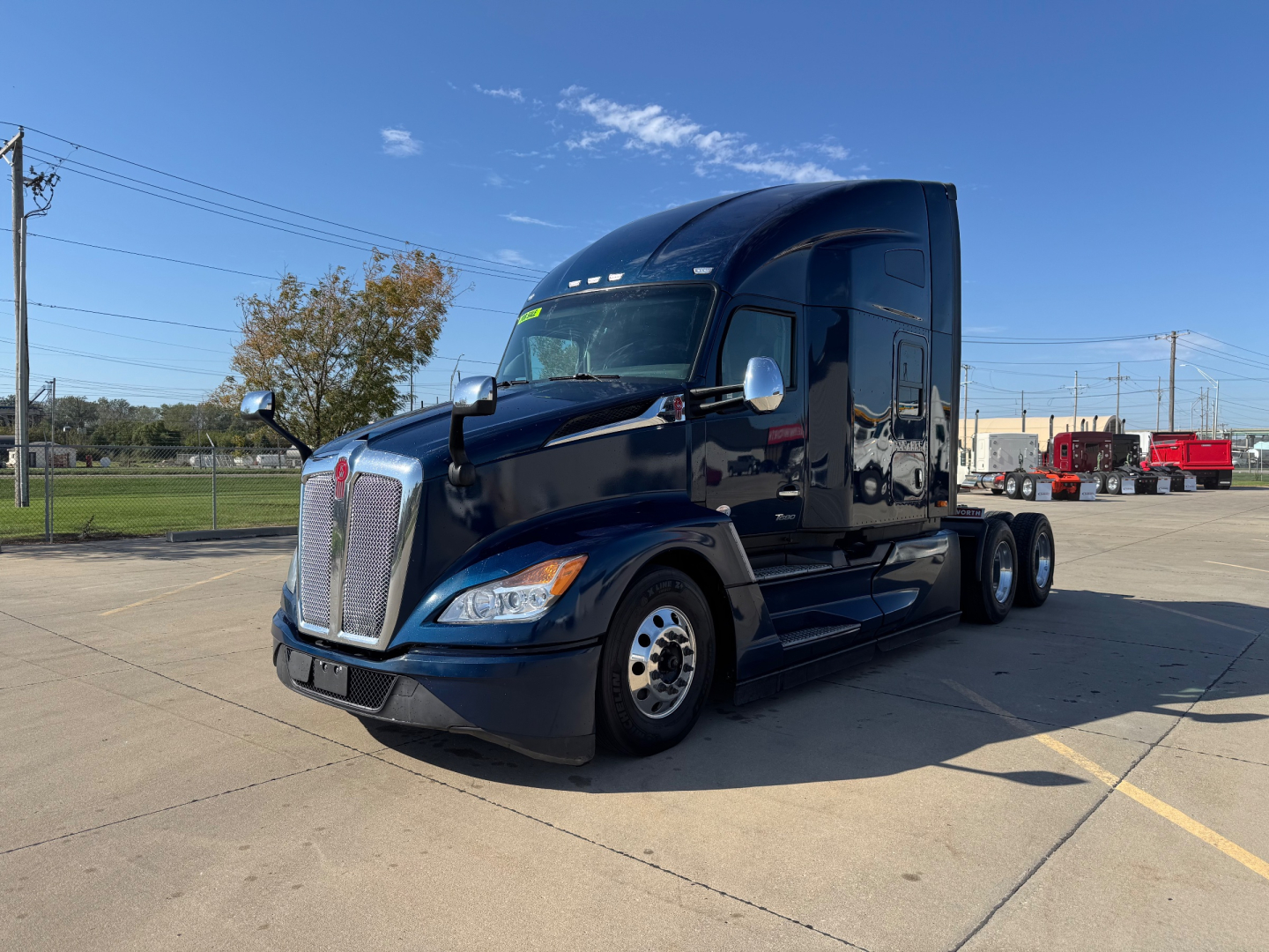Kenworth T680 tractor in a dealership lot showing front and side profile with glossy black paint and chrome accents.