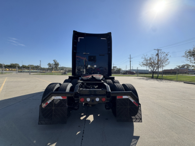 Kenworth T680 rear view showing fifth wheel, dual rear axles, and mudflaps in a paved lot.
