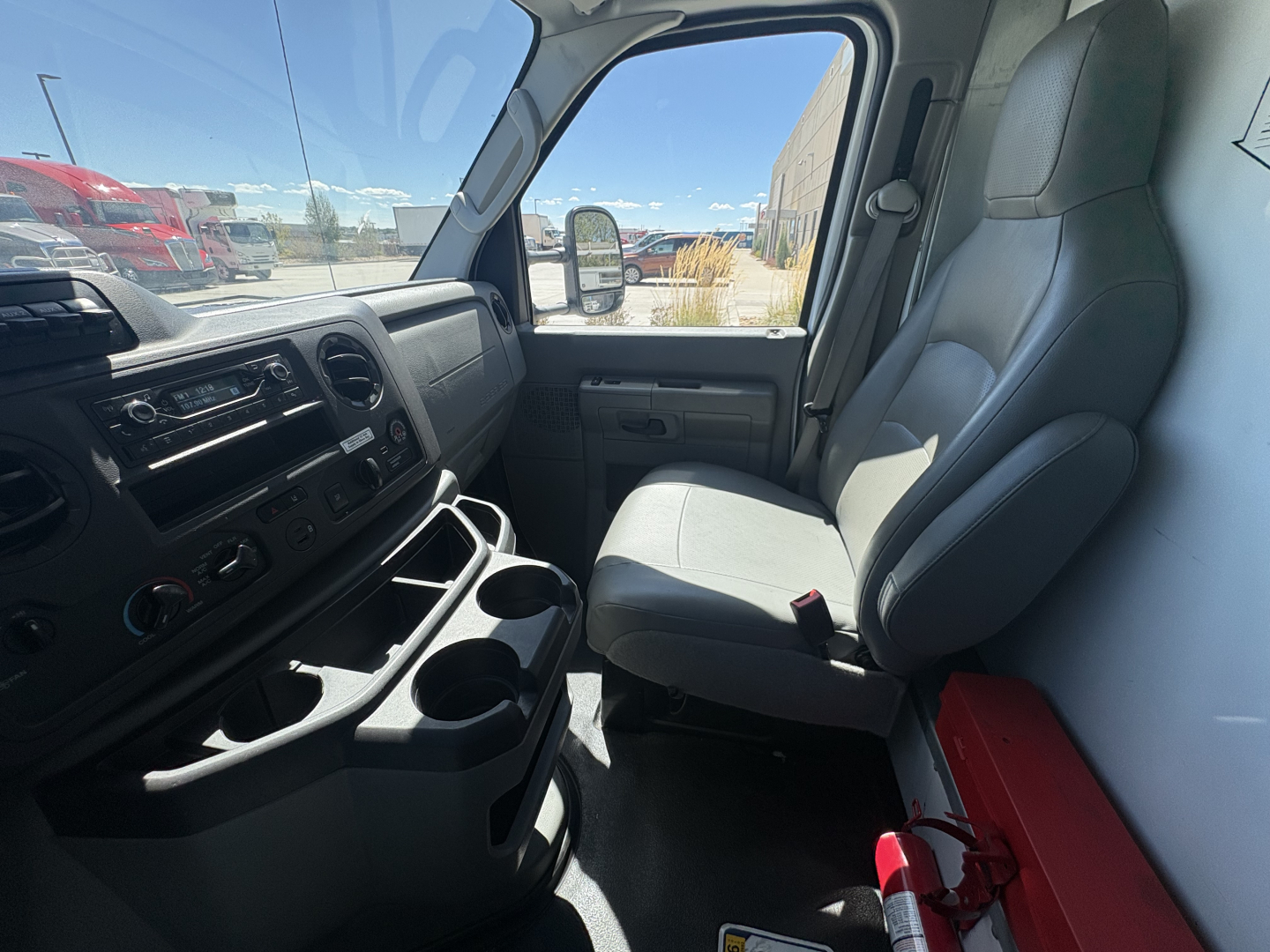 Ford E350 cab interior showing front seats and dashboard with cup holders and storage compartments.