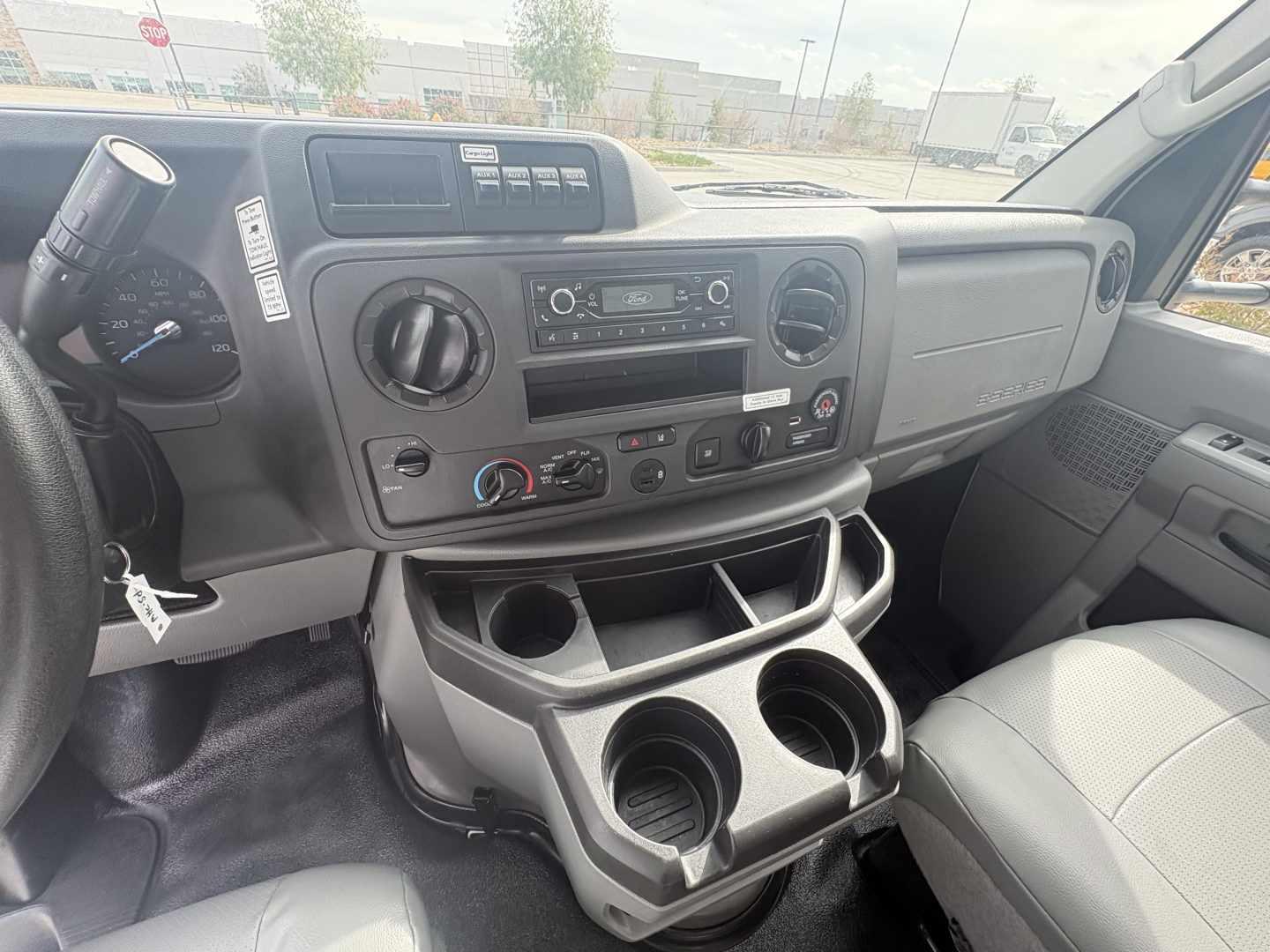 Dashboard of a 2022 Ford E350 cargo van interior showing center console with radio, climate controls, and cup holders. Visible text: nothing legible beyond typical controls.