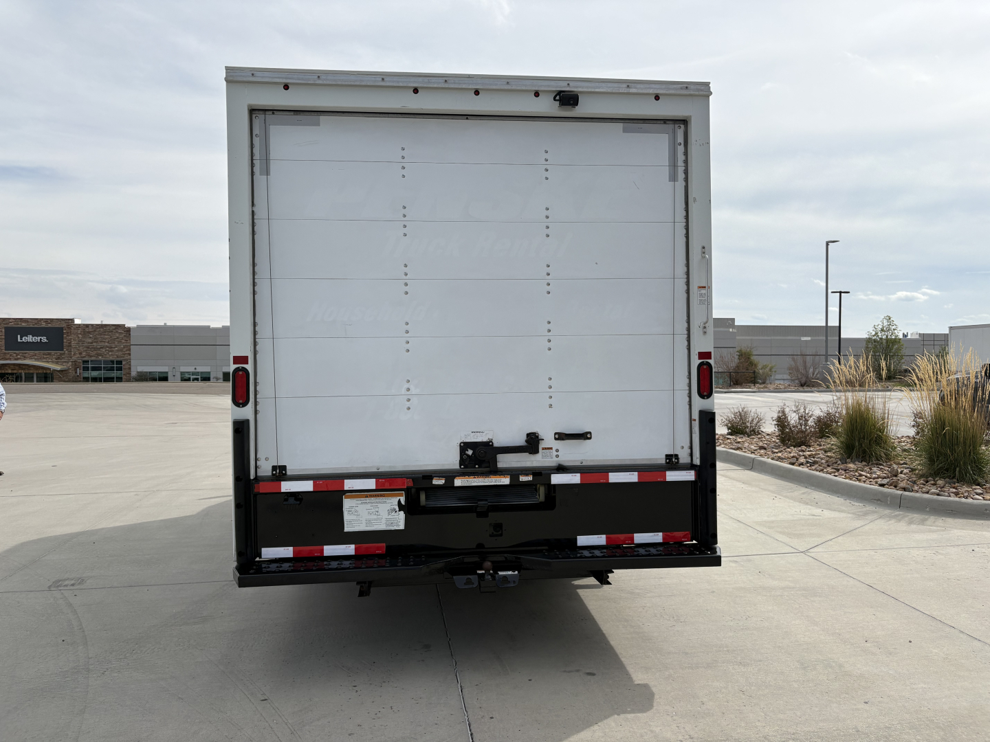 Rear view of a Ford E-350 box truck with a white cargo door, taillights, and a black bumper. There is no visible branding text on the back besides vehicle hardware.