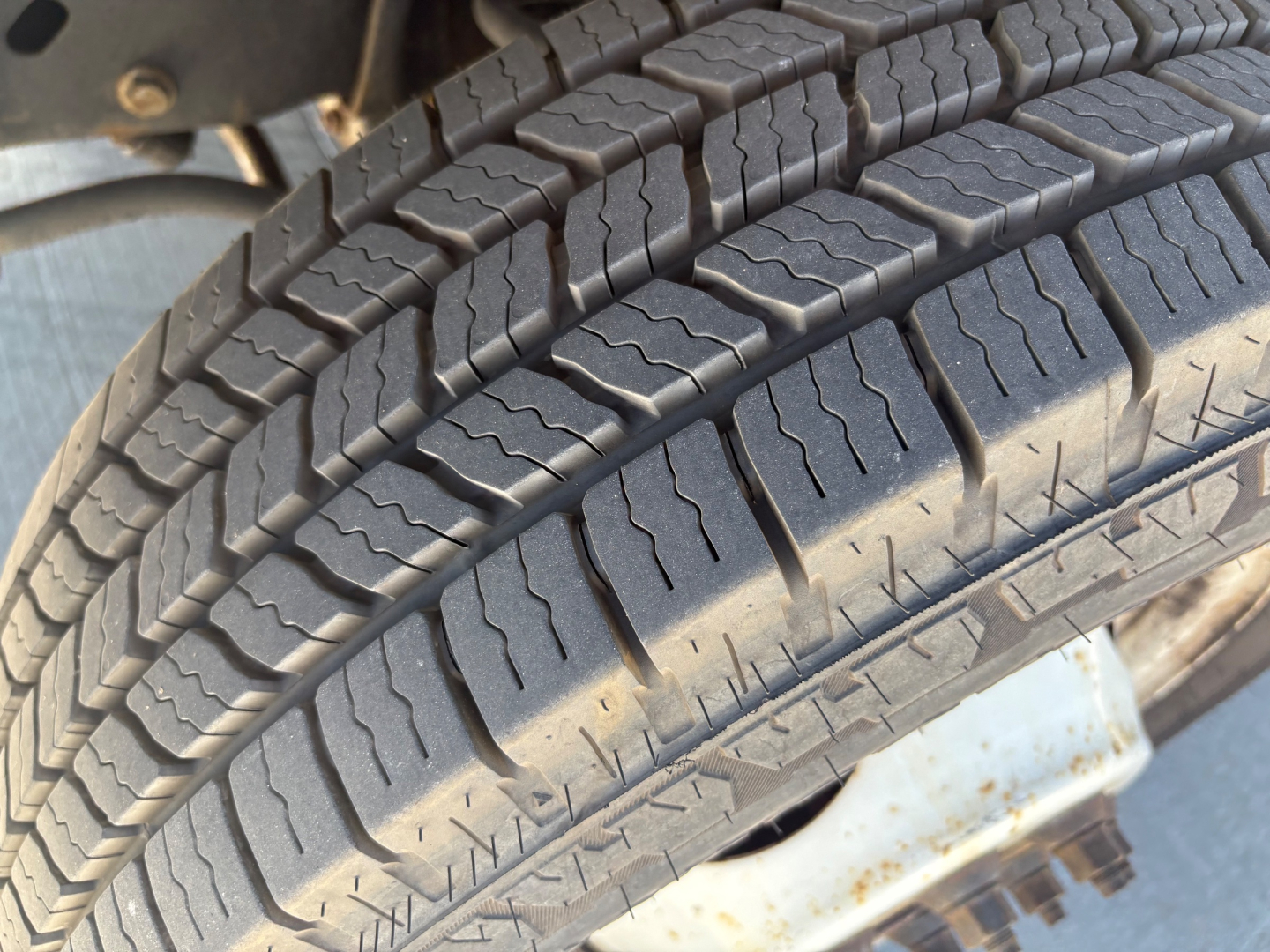 Ford E350 wheel tire close-up showing tread pattern and part of wheel well.