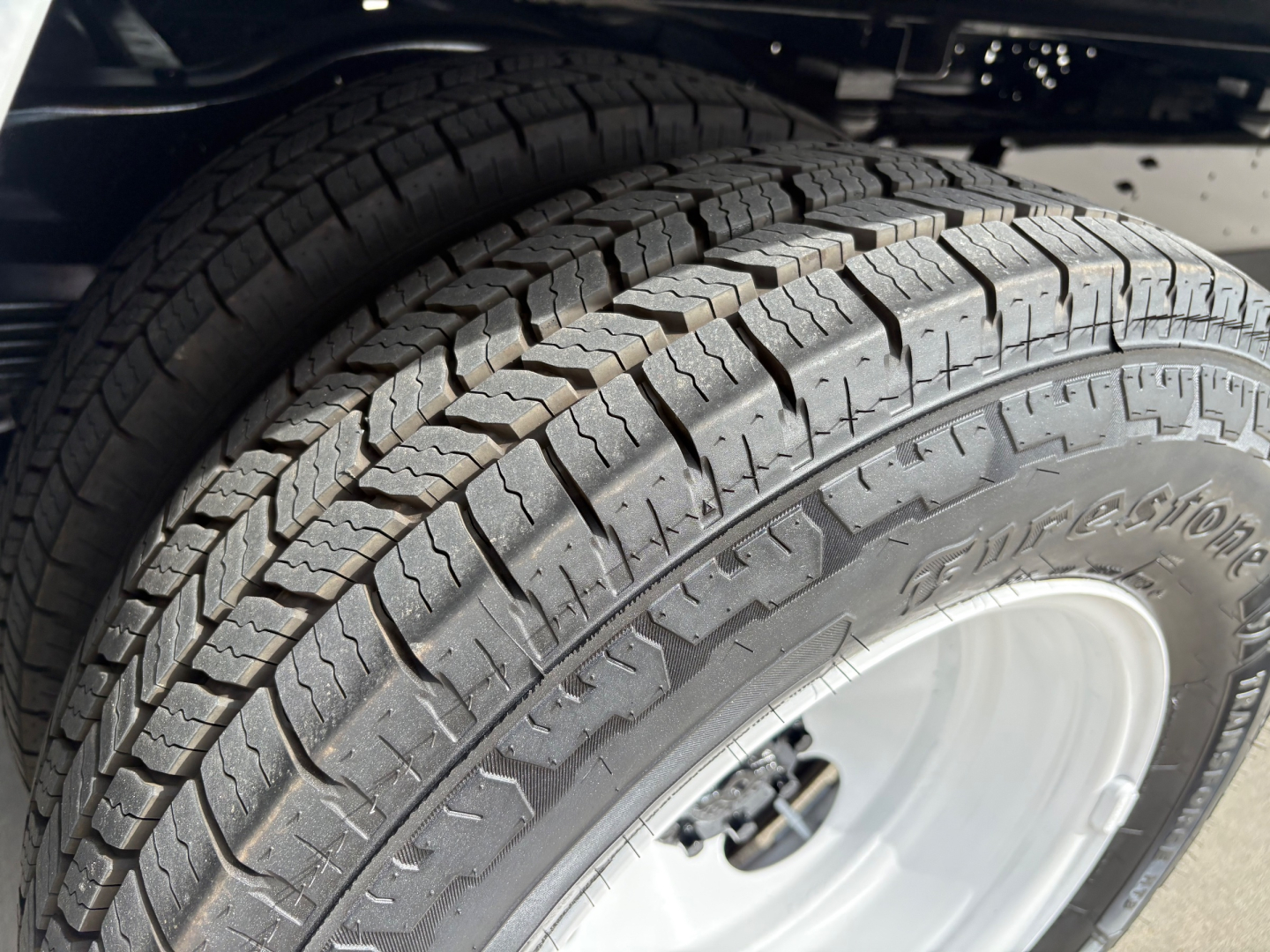 Ford E-Series van cutaway wheel with Goodyear tire, tread pattern and alloy wheel. Visible tire sidewall shows partial brand marking, tread blocks.