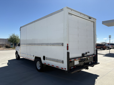 Box truck rear three-quarter view showing enclosed cargo box with rear doors and bumper, Ford E350 white cargo van truck.