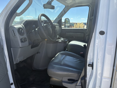 Ford E-350 interior front cab view showing steering wheel, dashboard, driver seat, and center console.