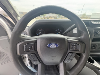 Ford steering wheel in cab showing instrument cluster and dashboard of a 2022 Ford E350 high roof cargo van.
