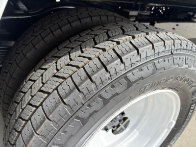 Ford E-Series van cutaway wheel with Goodyear tire, tread pattern and alloy wheel. Visible tire sidewall shows partial brand marking, tread blocks.
