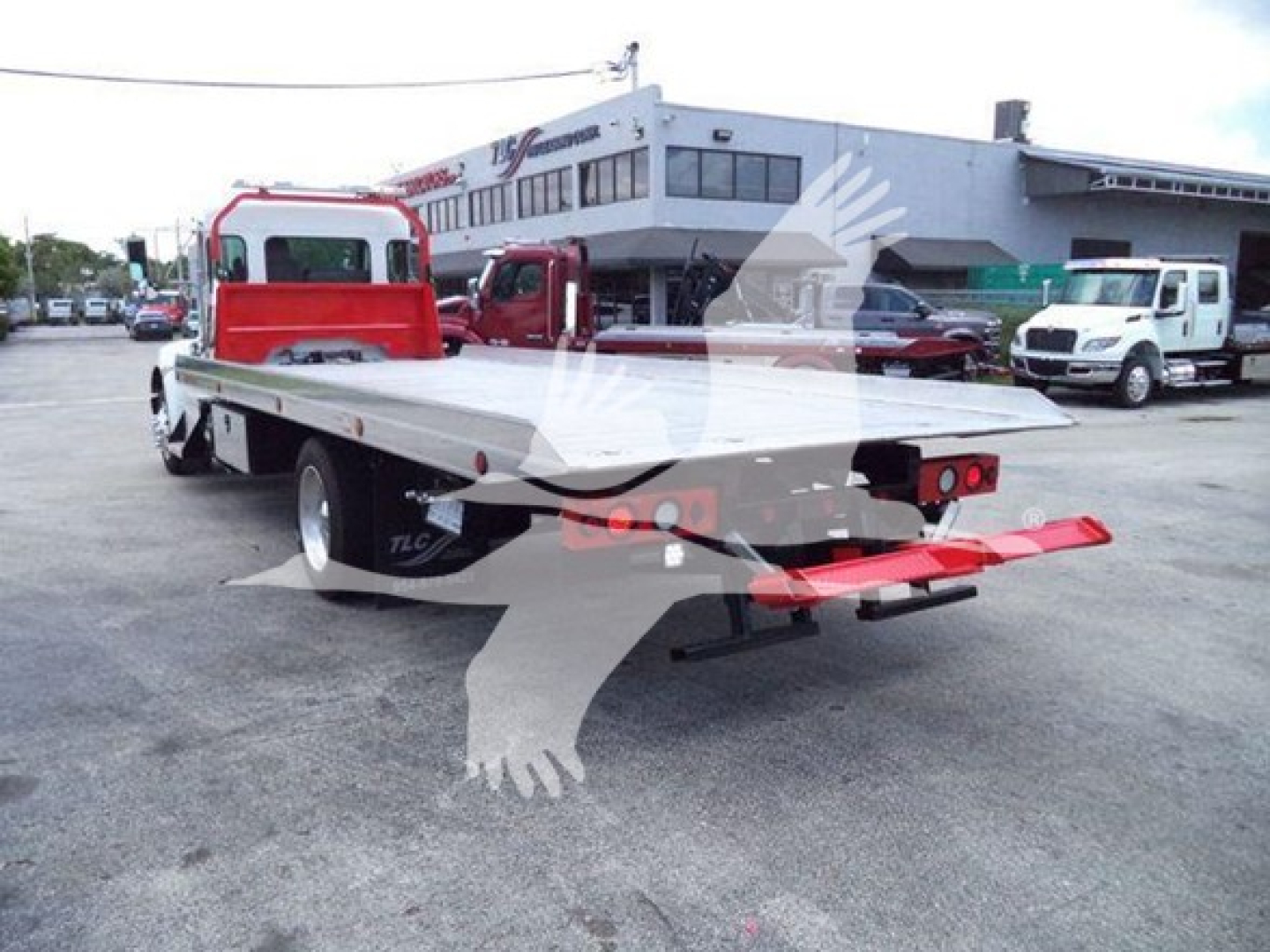 Kenworth T270 rollback wrecker in rear three-quarter view showing long flatbed and red towing underlift with tail lights; cabin and cab-over area visible.