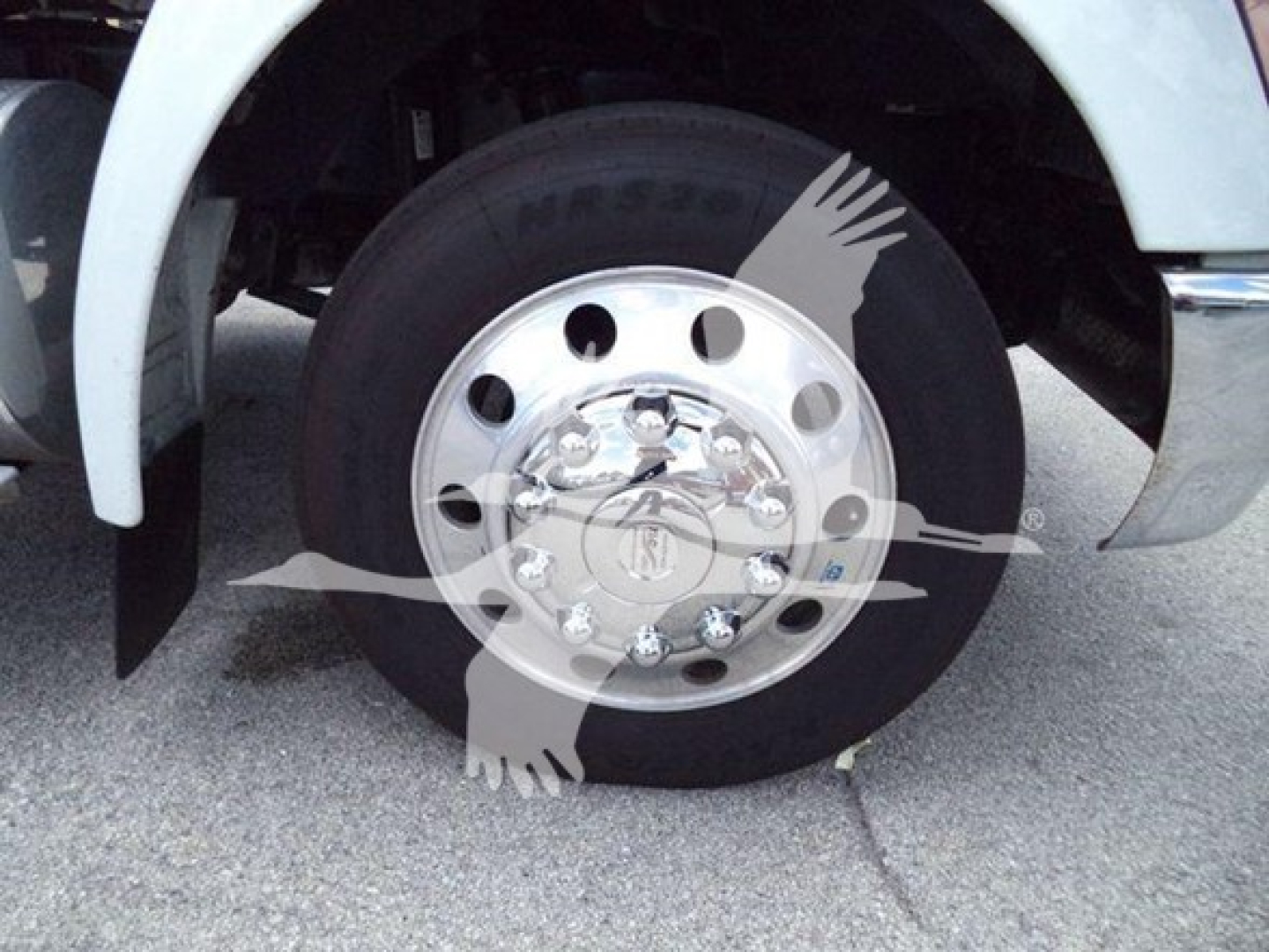 Truck wheel and front fender area showing a large chrome hubcap and black tire on Kenworth T270 rollback truck.
