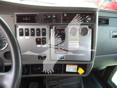 Dashboard of a Kenworth T270 showing control switches, gauges, warning stickers, and a yellow knob near the lower right; visible text includes various panel labels and warning stickers.