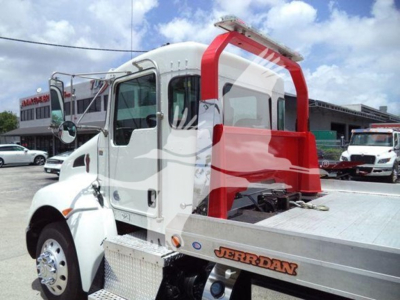 Kenworth T270 rollback truck with white cab and aluminum flatbed, red rear structure, side mirror, and 'JERRDAN' logo on bed; image shows truck in lot.