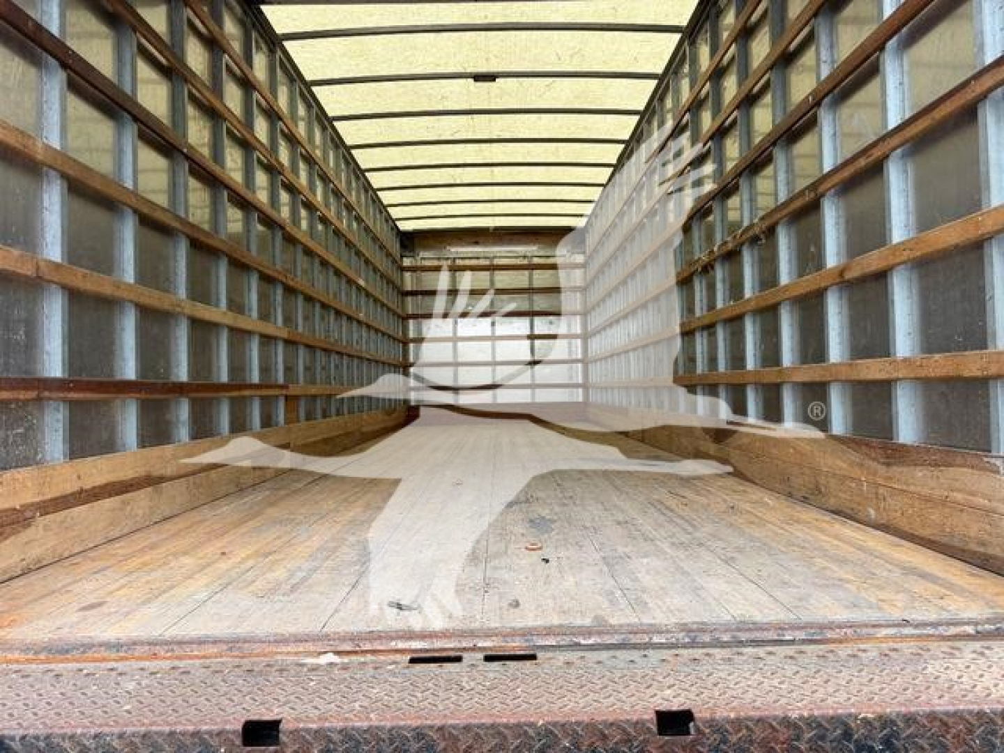 Truck cargo area of a 2020 International MV showing empty metal box interior with wooden side rails and a ribbed floor.