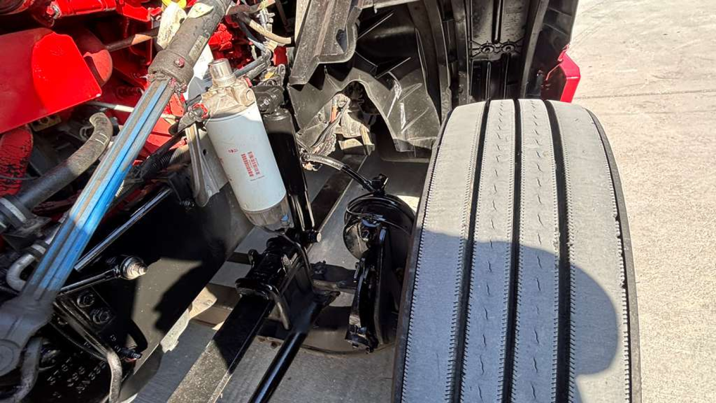 Truck front-axle area showing suspension components and hydraulic reservoir in a used 2022 International LT625 sleeper.