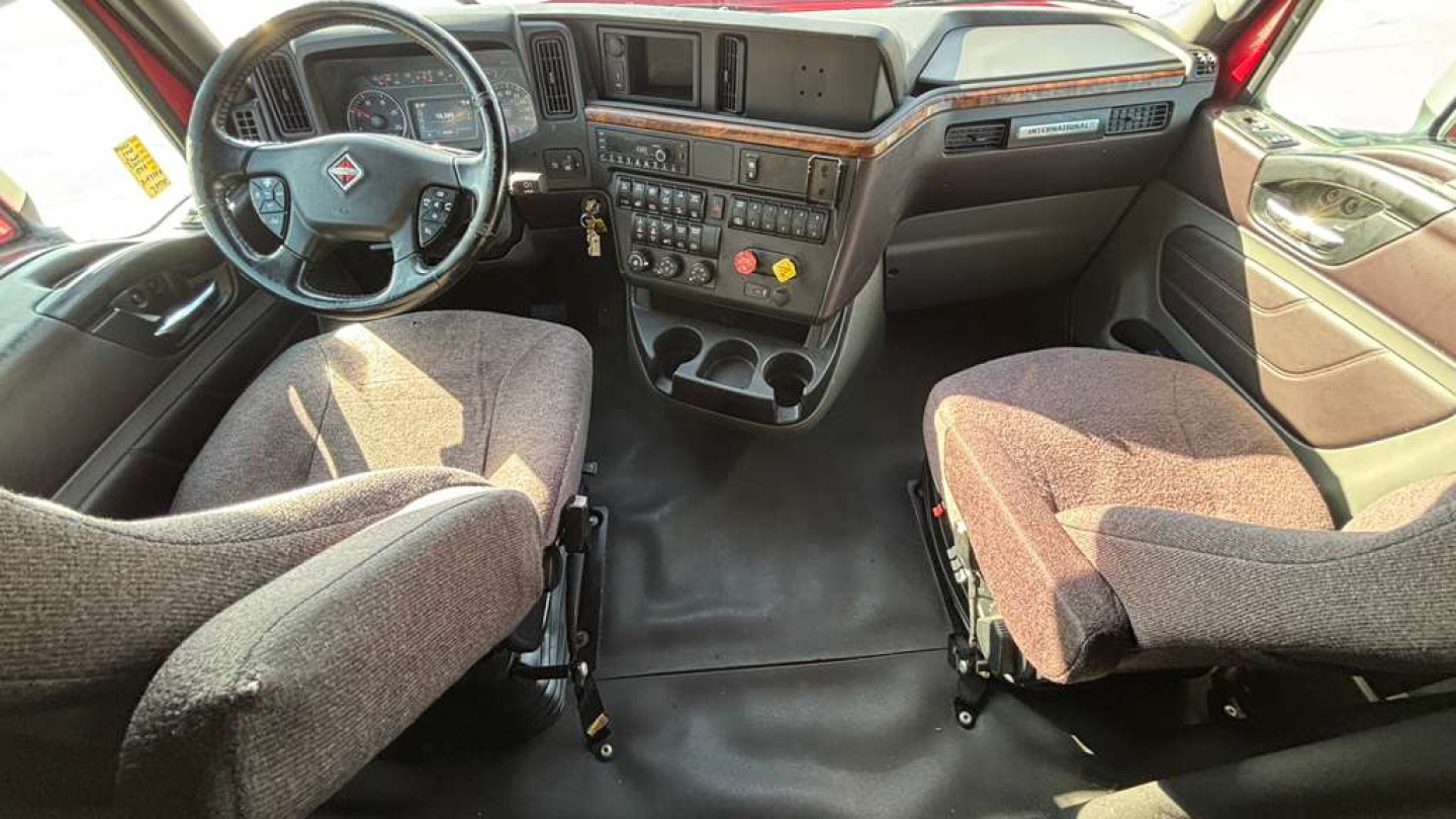 Interior of a 2022 International LT625 sleeper truck cab showing front seats, dashboard, and center console with steering wheel on left side.