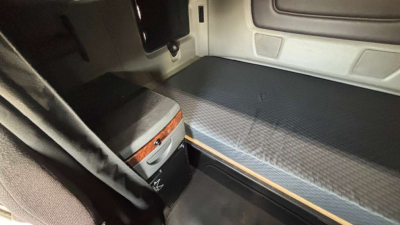 Interior cargo area of a 2022 International LT625 sleeper cab showing rear storage area, step board, and fabric-covered floor with side panel trim.