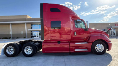 Commercial truck side view showing red 2022 International LT625 sleeper cab with chrome wheels and dual rear axles.
