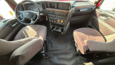 Interior of a 2022 International LT625 sleeper truck cab showing front seats, dashboard, and center console with steering wheel on left side.