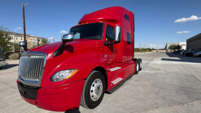 Red 2022 International LT625 tractor-trailer with sleeper cab, chrome grille, and side mirrors in a parking lot.