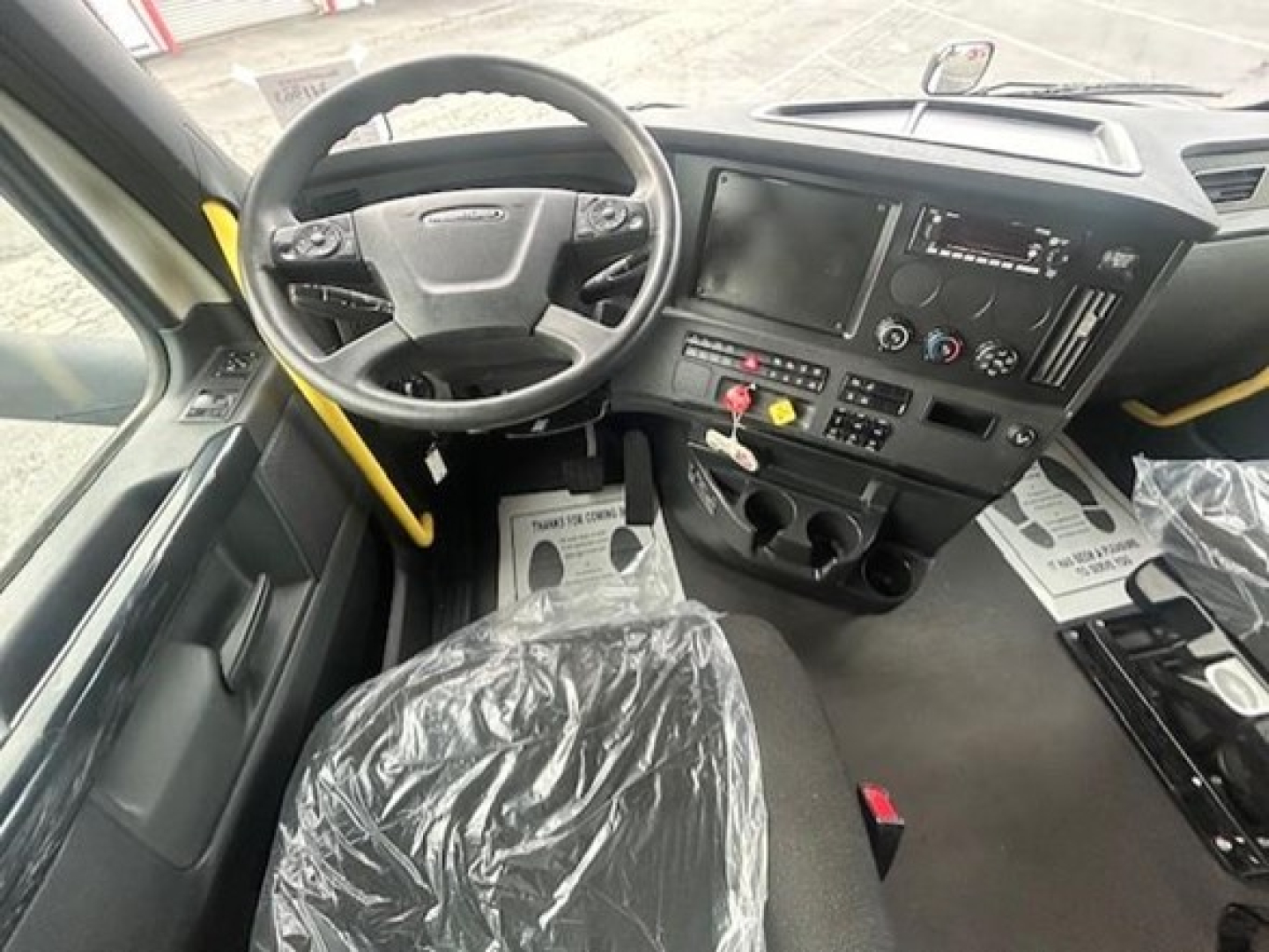 Cab interior of a Freightliner Cascadia 126 truck showing steering wheel, dashboard, and center console with touchscreen display and control buttons.