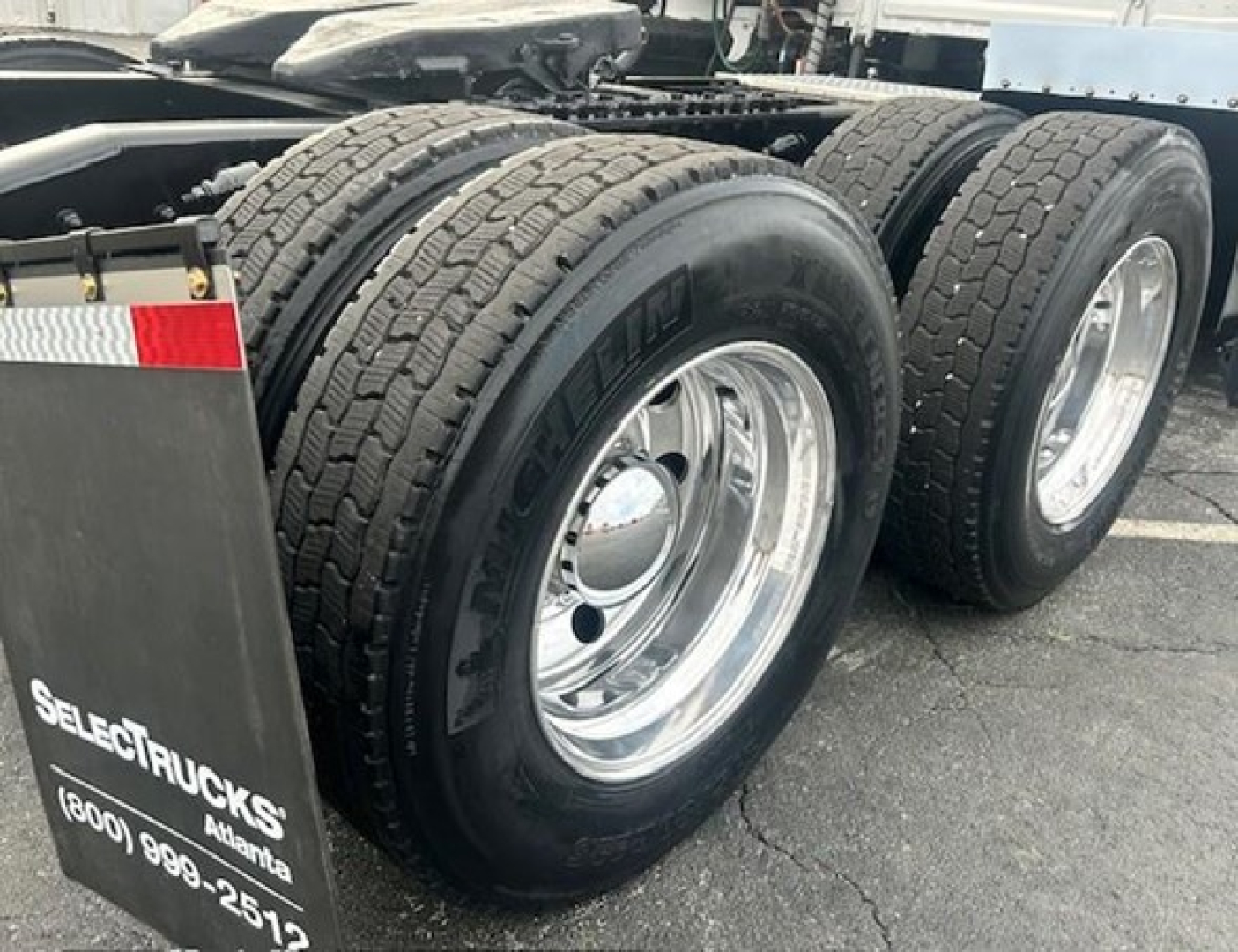 Freightliner Cascadia 126 truck rear dual wheels showing heavy-duty tires and chrome rims with mudflap branding.