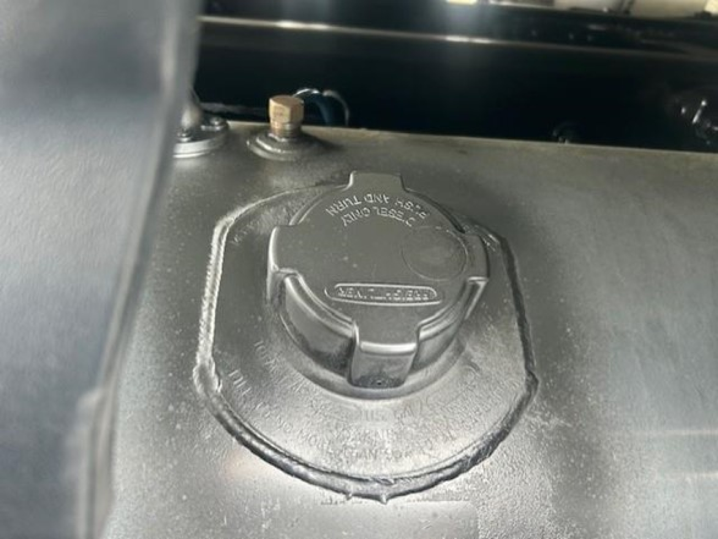 Fuel tank cap area of a Freightliner Cascadia 126 engine bay showing circular fuel cap with raised text.