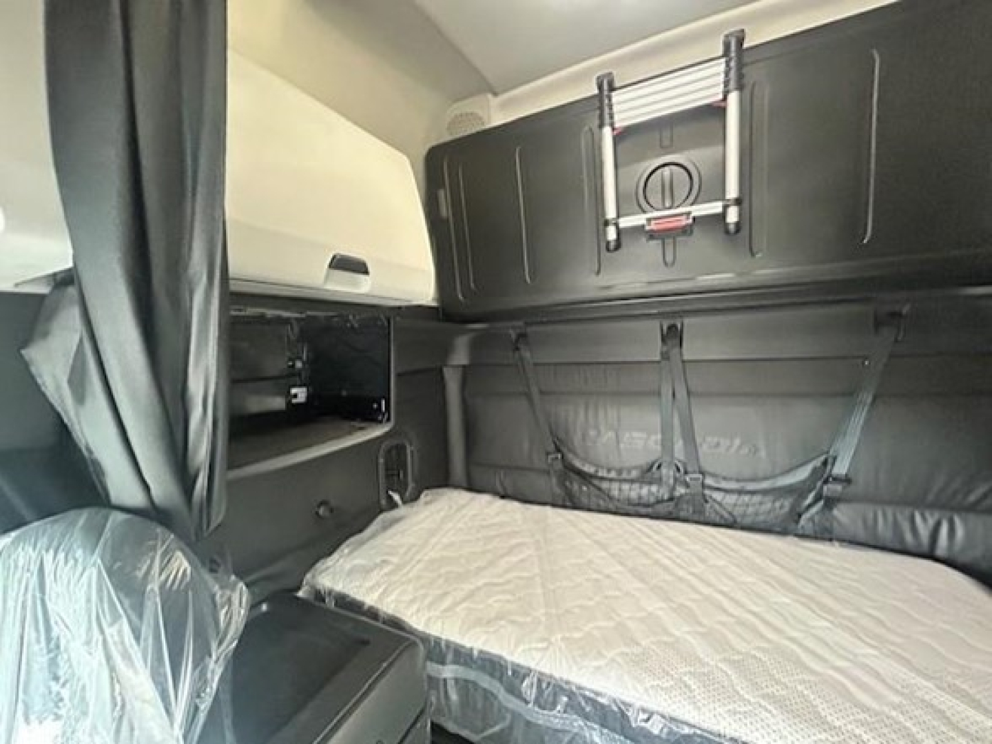 Freightliner Cascadia 126 sleeper cab interior with bed and overhead storage, captioned by the image of a compact sleeper area.