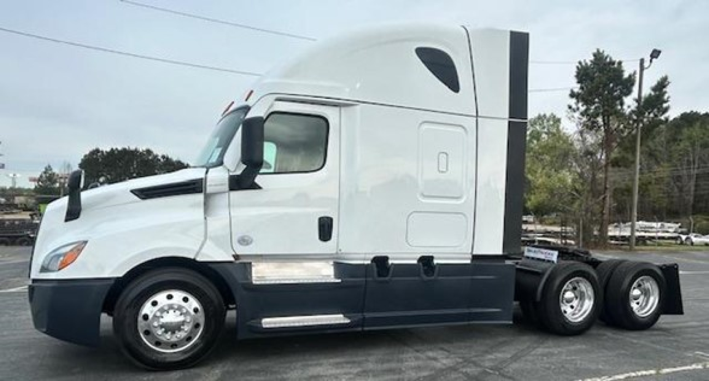 Truck cab showing Freightliner Cascadia 126 sleeper with white exterior and dark lower trim, side mirrors, and 6-wheel rear assembly.