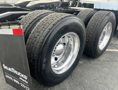 Freightliner Cascadia 126 truck rear dual wheels showing heavy-duty tires and chrome rims with mudflap branding.