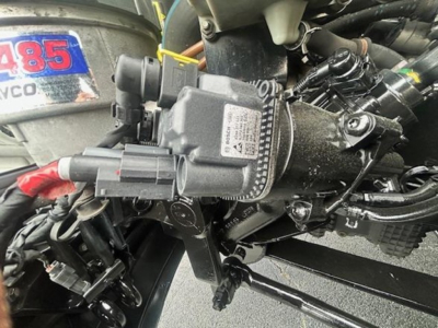Freightliner Cascadia diesel engine bay showing manifold and wiring harness with diagnostic plug and label visible.