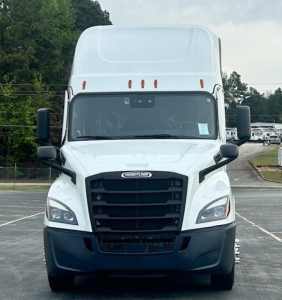 Truck front view of a white 2024 Freightliner Cascadia 126 in a dealer lot, with black grille, headlights, and large cab.