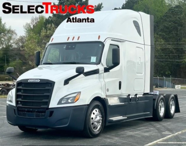 Freightliner Cascadia 126 sleeper tractor in white with black grille and bumper, three axles at rear, from a dealership lot.