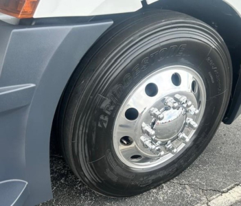 Front wheel close-up of 2024 Freightliner Cascadia 126 showing Bridgestone tire and chrome hubcap in truck bay.