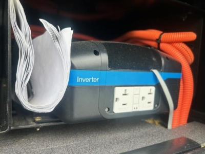 Inverter unit with blue stripe labeled Inverter and two standard electrical outlets inside a Freightliner Cascadia 126 engine bay area.