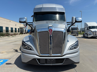 Kenworth T680 front view showing large chrome grille, Kenworth emblem, dual hood vents, and projector headlights in a silver truck.