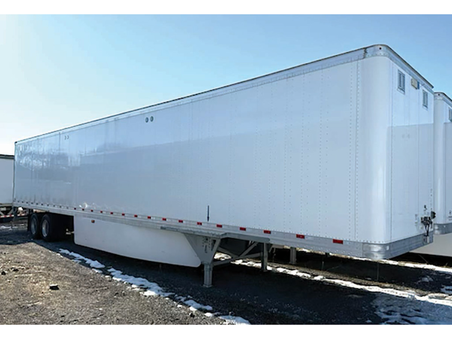 Aluminum trailer/van showing smooth riveted side panels and support legs.