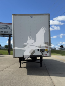 Rear view of a white trailer with a graphic of a person reaching upward, on a trailer in a parking lot.