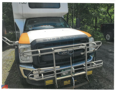 Front view of a 2016 Ford F-550 Super Duty bus with a metal brush guard and orange fender accents.