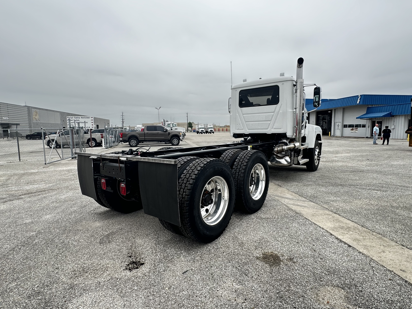 Mack PI64 cab and chassis truck rear and side view showing dual rear axles and chassis frame with cab in background.