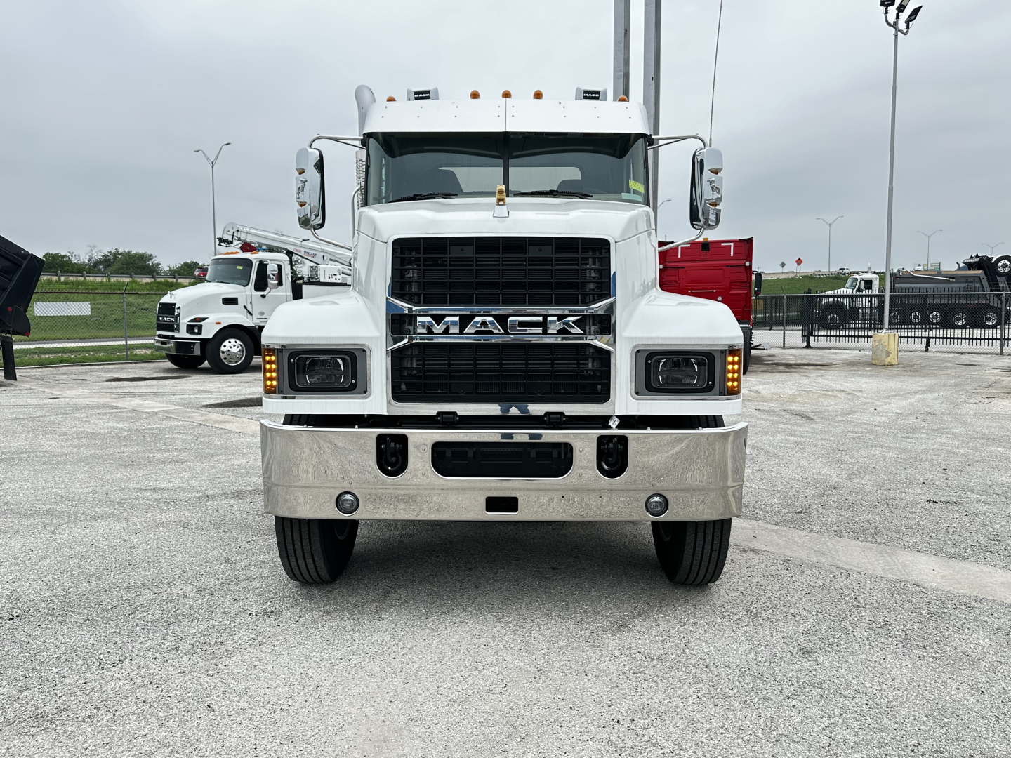 Front view of a white Mack PI64 cab and chassis truck showing MAC K grille, large bumper, and daytime running lights.