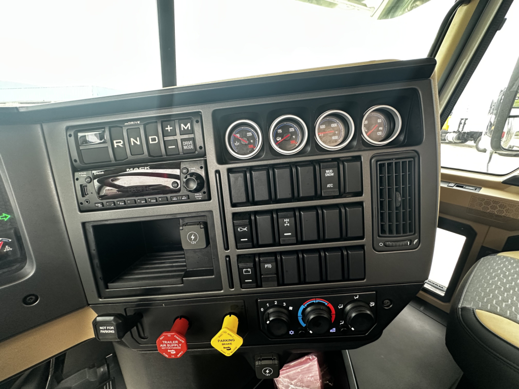 Dashboard view of a 2026 Mack PI64 cab and chassis showing gear selector, multiple gauges, switches, and climate controls.