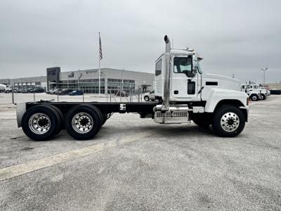 KIMG_ shown white Mack PI64 cab and flatbed chassis side view with dual rear axles.