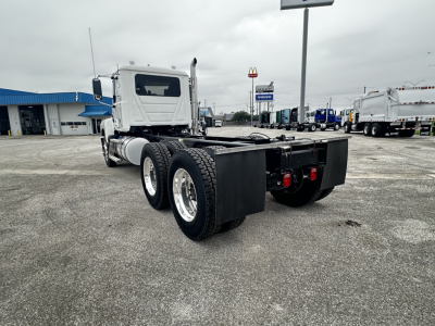 2026 Mack PI64 cab and chassis rear view showing dual rear axles and flatbed coupling with large black toolbox boxes and tires.