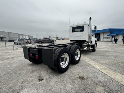 Mack PI64 cab and chassis truck rear and side view showing dual rear axles and chassis frame with cab in background.