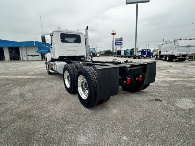 Mack PI64 cab and chassis rear/side view showing dual rear axles and flatbed chassis with frame, tires, and basic rear bumper components.